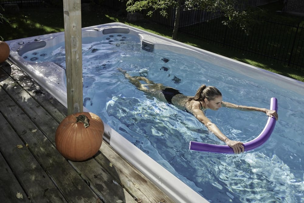 woman swimming with floating tube in swim spa